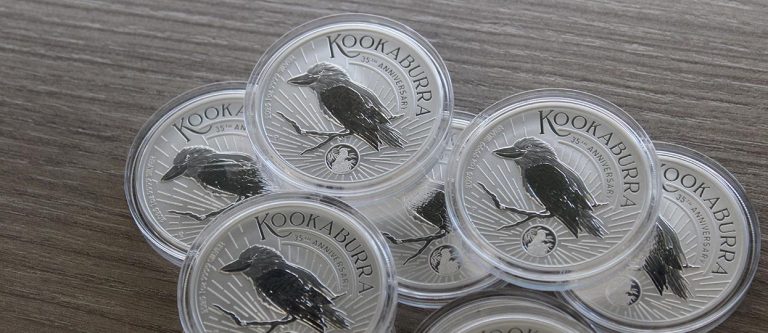 Monedas de plata Kookaburra de 1oz de 2025 edición especial del 35 aniversario, apiladas sobre un suelo de madera