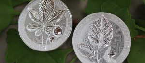 Dos fabulosas monedas de la colección Mythical Forest de Germania Mint, sobre hojas de un árbol