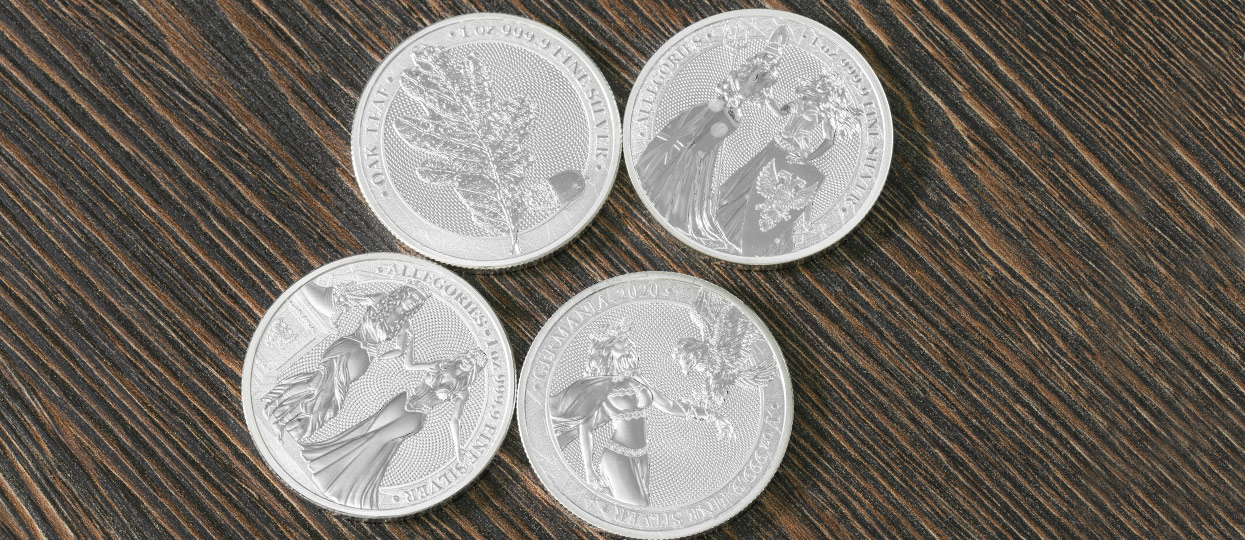 Varias monedas bullion de la ceca Germania Mint, sobre una mesa de madera