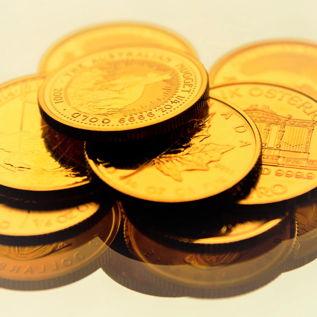 Varias monedas de oro de 1 onza de diferentes cecas, situadas sobre un espejo