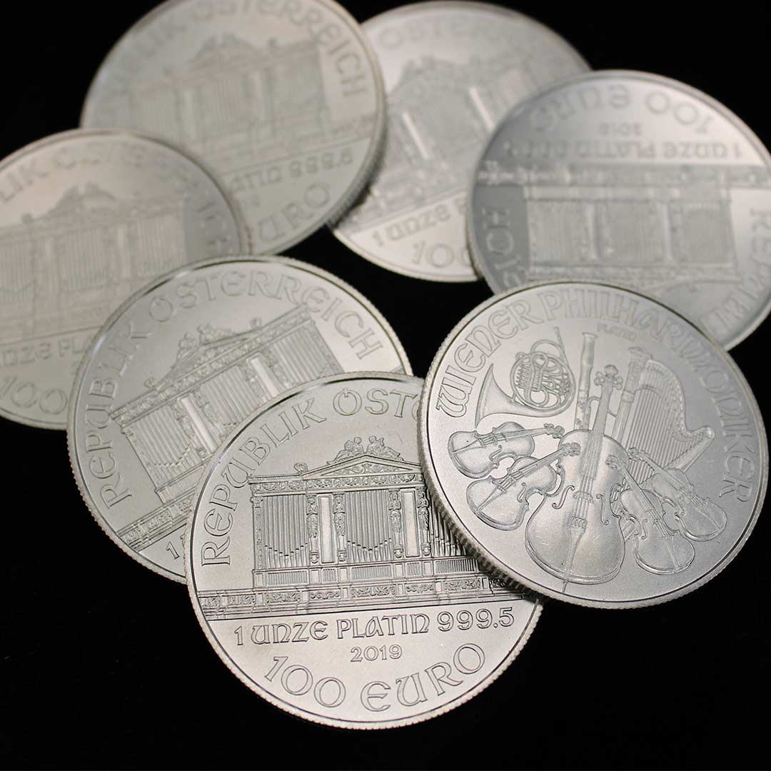 Una moneda de 1 onza de paladio Emú y una moneda de 1 onza de plation Royal Arms, sobre un tapete oscuro