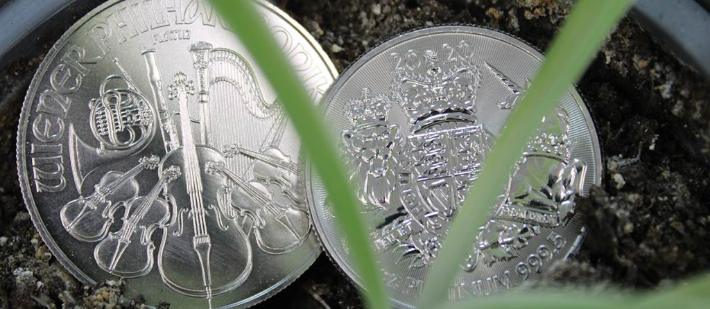 Monedas de platino Filarmónica de Viena y Rotal Arms encima de una maceta de tierra