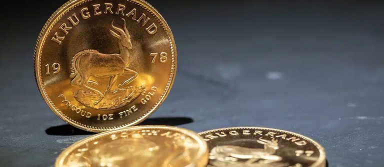 Monedas de oro Krugerrand de diferentes años sobre un suelo azul oscuro