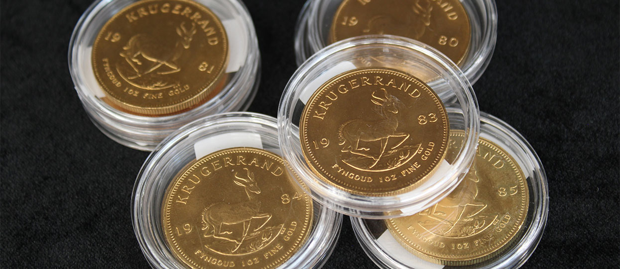 Monedas de oro Krugerrand protegidas con cápsula sobre un fondo negro