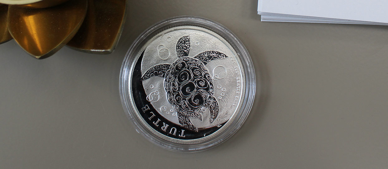 Moneda de plata de la Tortuga, sobre una mesa de metal