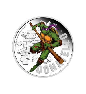 Perspectiva frontal de la cruz de la moneda de plata policromada Donatello de 1oz de 2025, que muestra a la tortuga portando su arma con un semblante serio