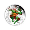 Perspectiva frontal de la cruz de la moneda de plata policromada Michelangelo de 1oz de 2025, que muestra al personaje irrumpiendo de un muro portando sus nunchakus